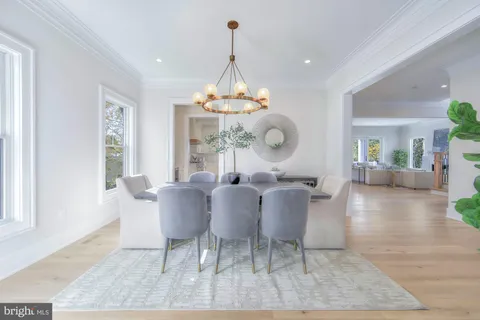 a dining room with wooden floor a chandelier a glass table and chairs