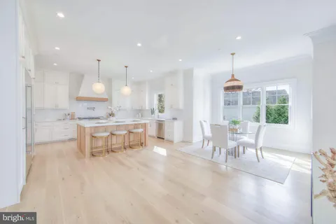 a large white kitchen with a sink a refrigerator and a wooden floor