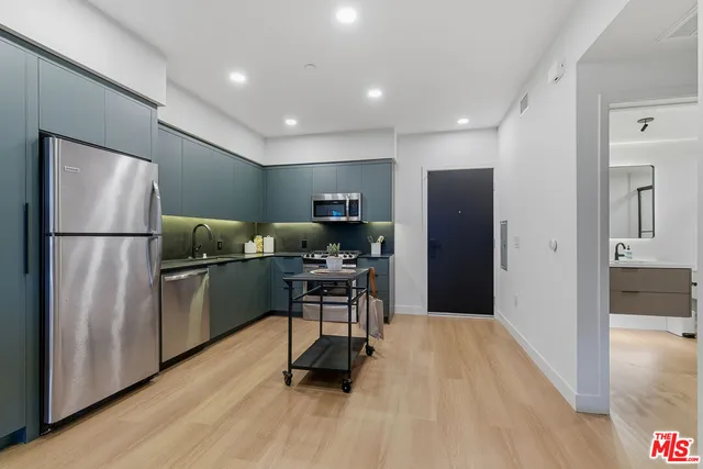 a kitchen with stainless steel appliances a refrigerator and wooden floor