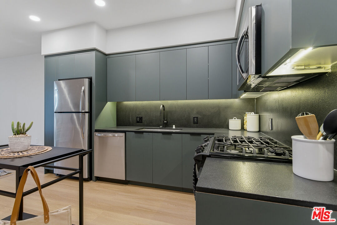 10601 Washington Boulevard, Unit 428 Culver City, CA 90232 - Photo 10 of 29 a kitchen with kitchen island a stove a refrigerator and a dining table with wooden floor