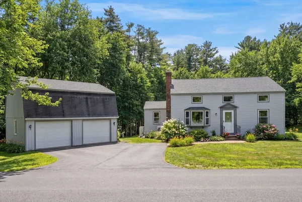a front view of house with yard and trees in the background