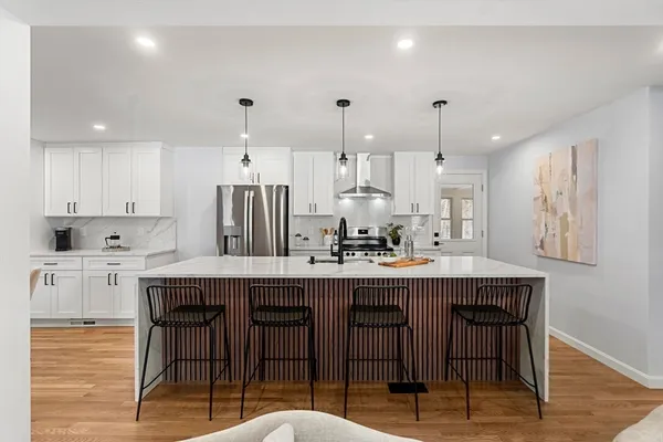 a kitchen with stainless steel appliances granite countertop a table chairs sink and cabinets