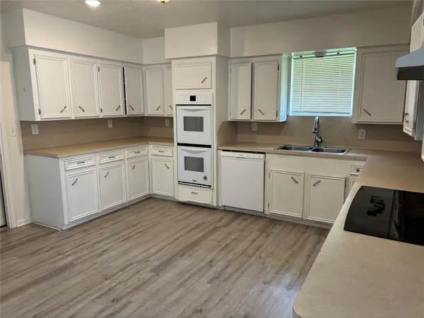 a kitchen with granite countertop a sink cabinets and wooden floor