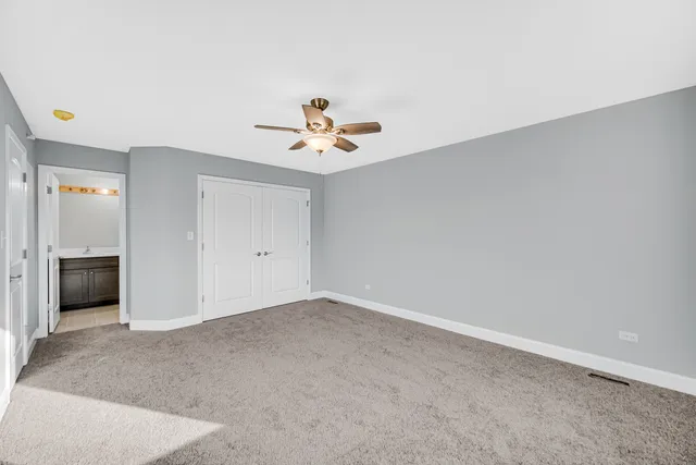 an empty room with closet and a ceiling fan