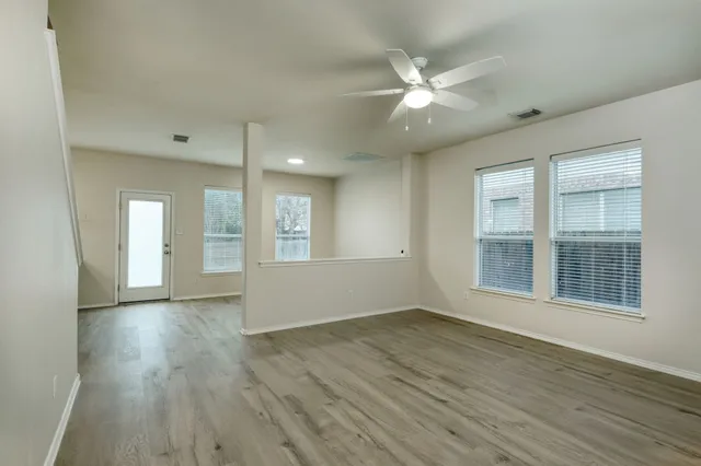 a view of an empty room with wooden floor and a window