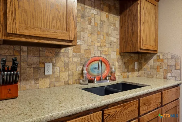 a kitchen with granite countertop a sink a stove and cabinets