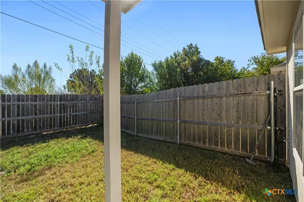 a view of a backyard with a plants and wooden fence