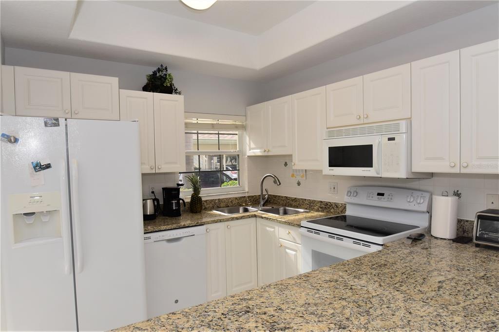4235 Castle Bridge, Unit 1216 Sarasota, FL 34238 - Photo 2 of 18 a kitchen with refrigerator a stove a sink a refrigerator and white cabinets