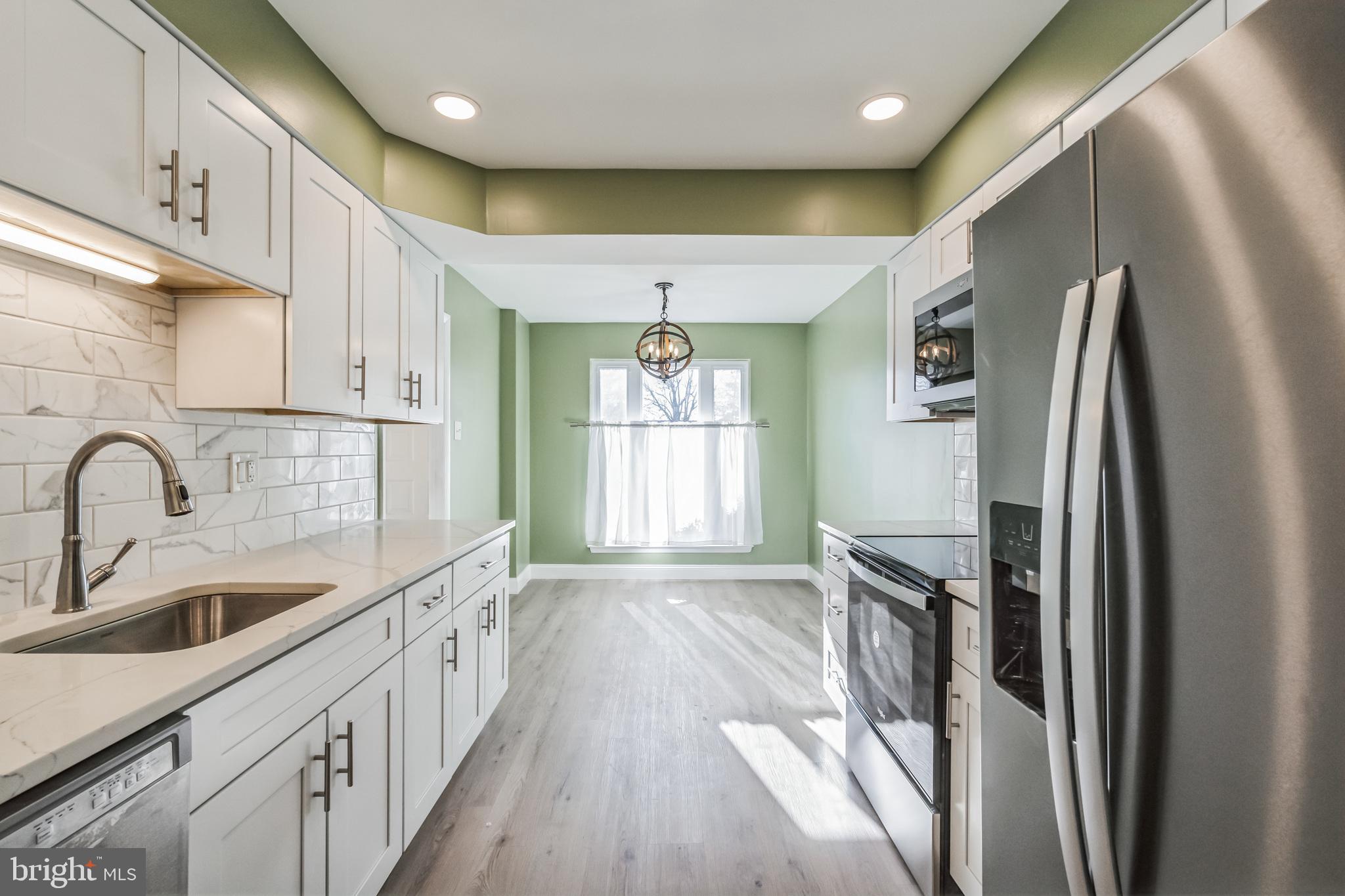 1179 Putnam Boulevard, Unit 3 Wallingford, PA 19086 - Photo 4 of 9 a kitchen with stainless steel appliances granite countertop a refrigerator a sink dishwasher a stove and a dining table with wooden floor