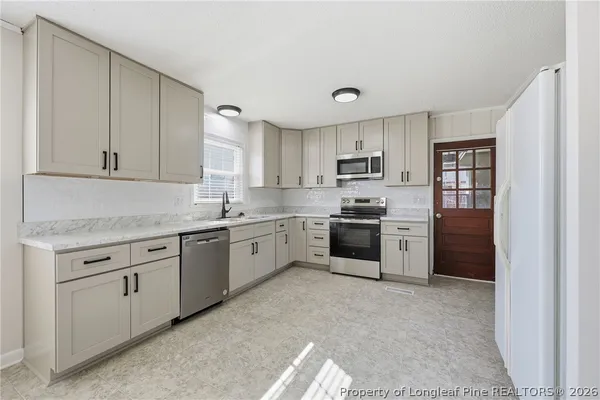 a kitchen with granite countertop white cabinets and stainless steel appliances