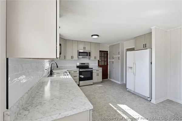 a large kitchen with a refrigerator a stove top oven a sink and dishwasher