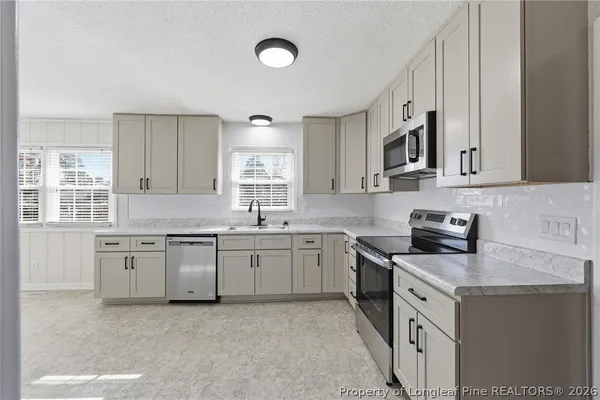 a kitchen with granite countertop a sink a stove a microwave and wooden cabinets