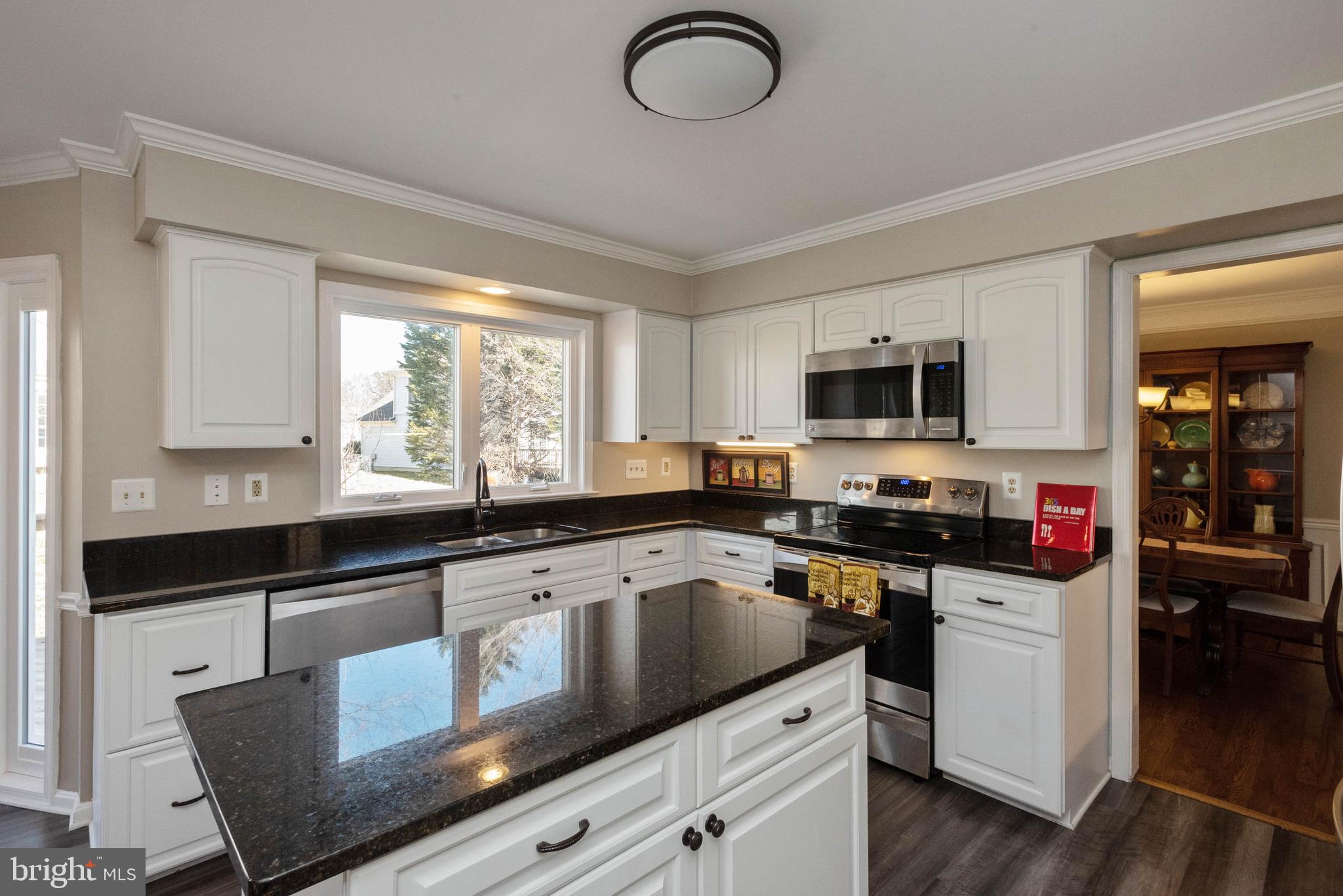 8608 Ashcroft Drive Laurel, MD 20708 - Photo 9 of 45 a kitchen with stainless steel appliances granite countertop a stove top oven a sink dishwasher a dining table and chairs with wooden floor