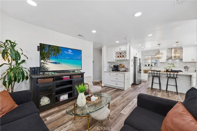 a living room with furniture and a flat screen tv with kitchen view