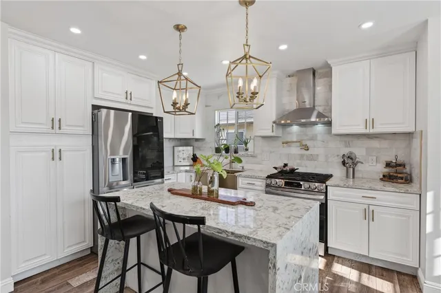 a kitchen with stainless steel appliances kitchen island granite countertop a sink a stove a refrigerator a center island and cabinets