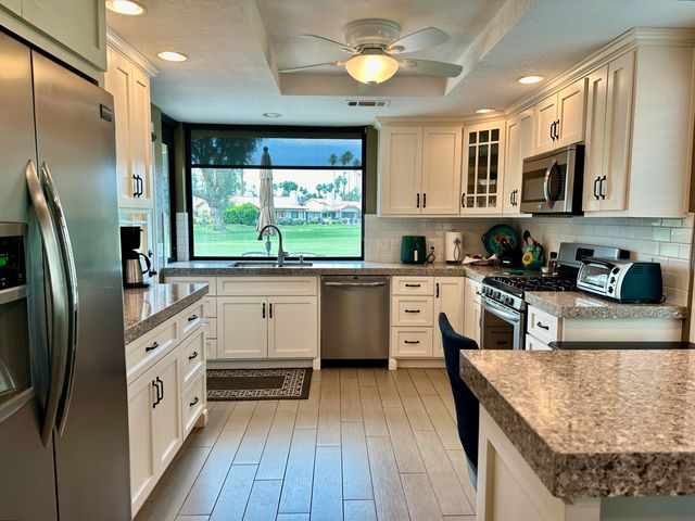 a large kitchen with stainless steel appliances granite countertop a lot of counter space and wooden floor