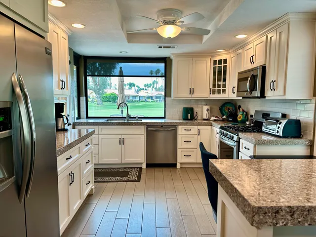 a large kitchen with stainless steel appliances granite countertop a lot of counter space and wooden floor