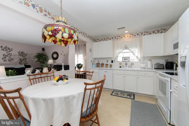 a kitchen with a dining table cabinets stainless steel appliances and a chandelier