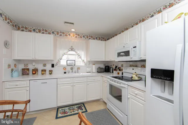 a kitchen with white cabinets and white appliances