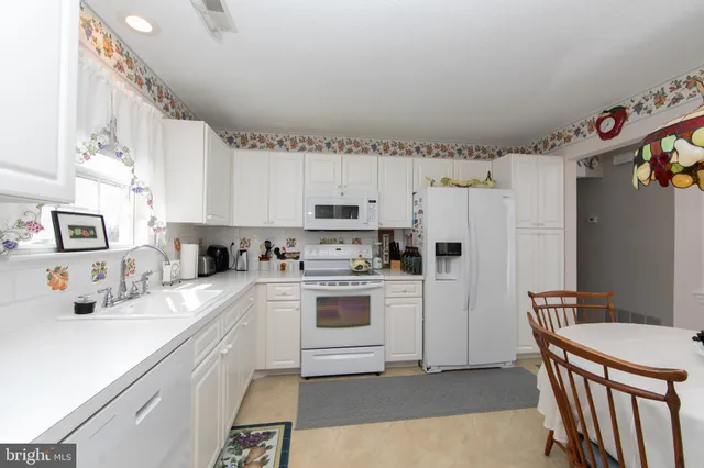 a kitchen with cabinets a sink and white appliances