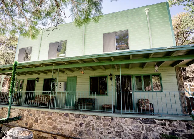 a view of a house with brick walls plants and large tree