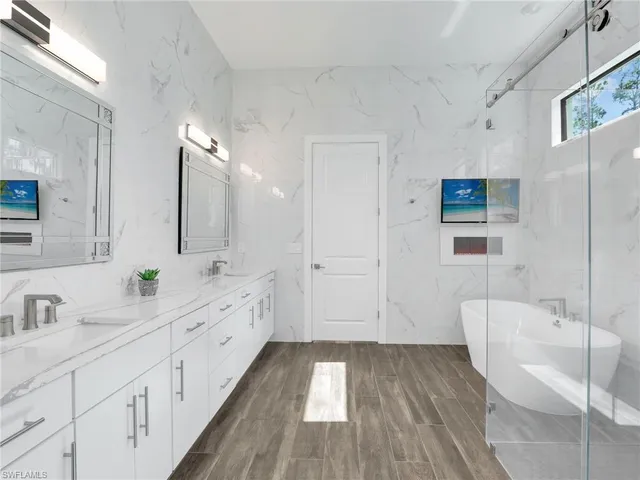 a spacious bathroom with a double vanity sink a mirror and a bathtub