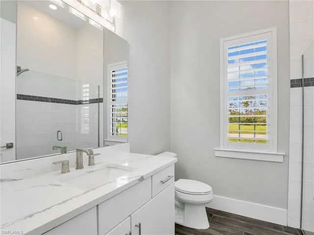 a bathroom with a granite countertop sink toilet and a mirror