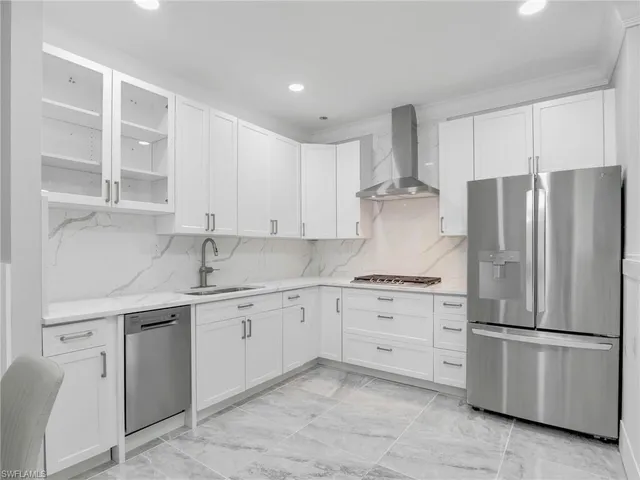 a kitchen with stainless steel appliances granite countertop a refrigerator sink and white cabinets