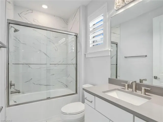 a bathroom with a granite countertop sink toilet a mirror and shower