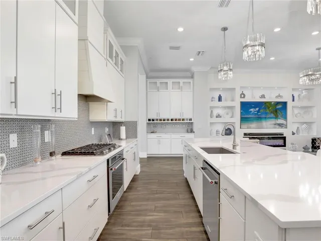 a large kitchen with stainless steel appliances kitchen island a large counter top a stove a chimney a sink and a refrigerator