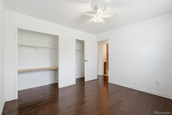 an empty room with wooden floor and ceiling fan