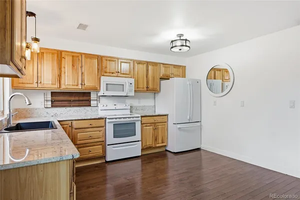a kitchen with granite countertop wooden floors appliances and sink