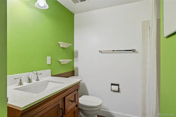 a bathroom with a granite countertop toilet and a sink