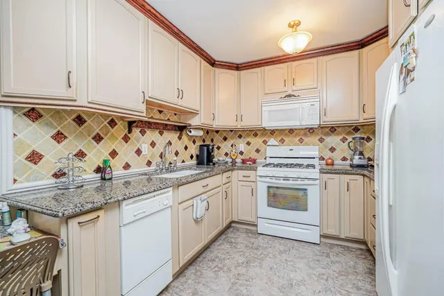 a kitchen with granite countertop white cabinets and white appliances