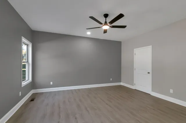 an empty room with wooden floor and windows