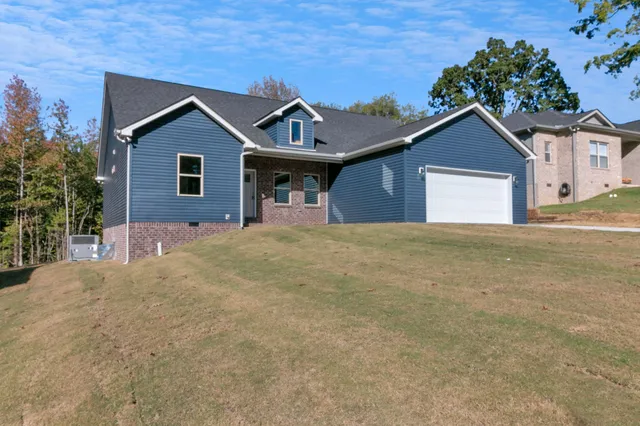 a view of a house with a yard and large tree