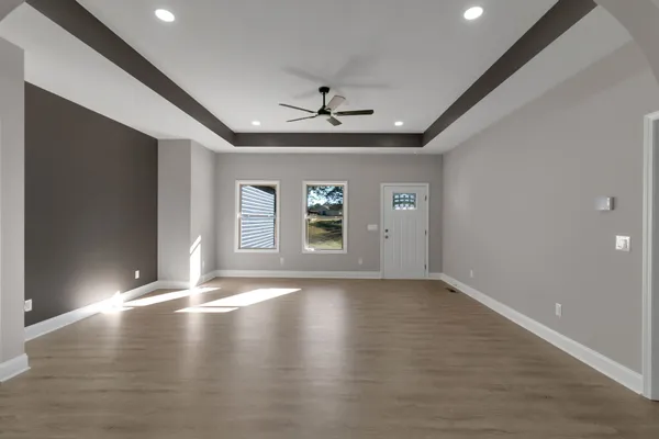 an empty room with chandelier fan and windows