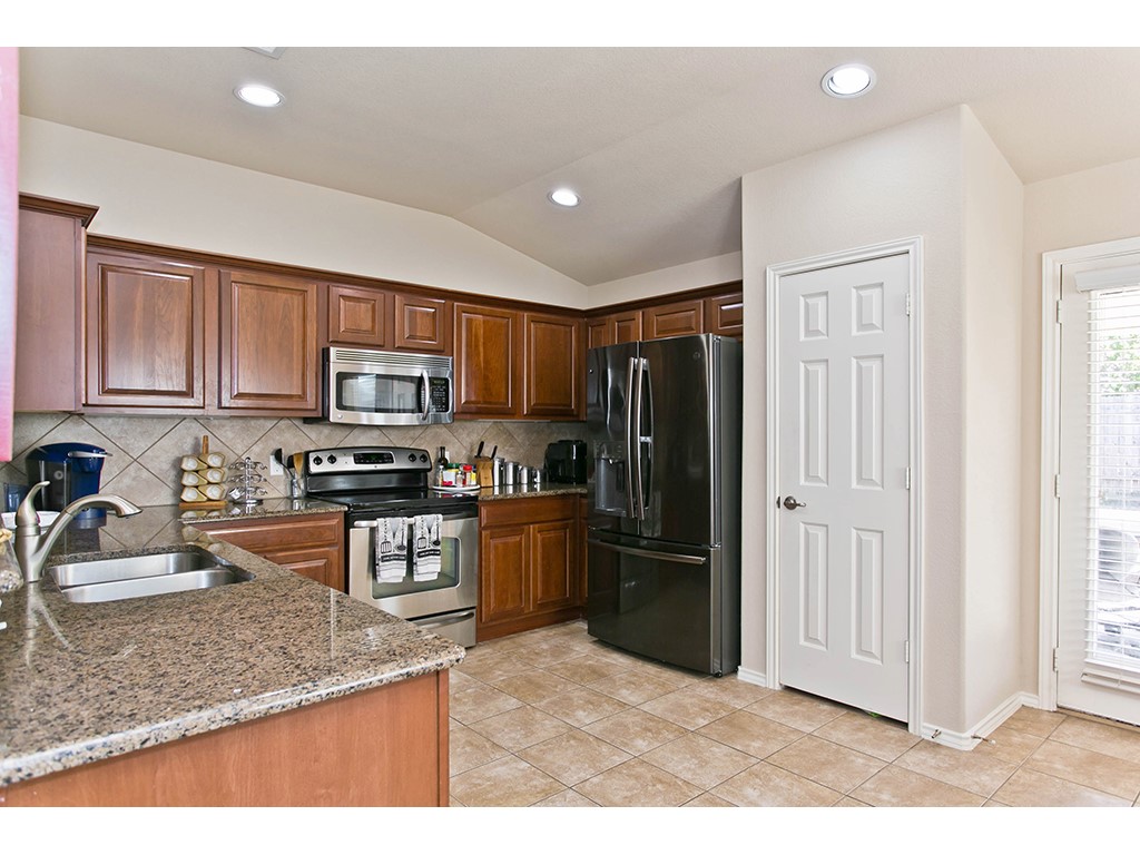 1808 Sand Creek Road Cedar Park, TX 78613 - Photo 7 of 25 Kitchen featuring wood cabinetry, stainless steel appliances, granite countertops, and tiled flooring