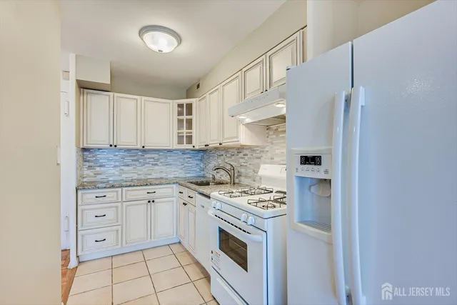 a kitchen with granite countertop white cabinets and refrigerator