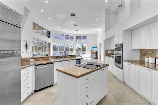 a kitchen with granite countertop kitchen island white cabinets and stainless steel appliances