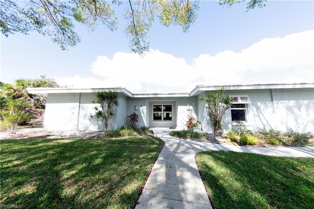 721 Springline Drive Naples, FL 34102 - Photo 2 of 7 a front view of a house with a yard and potted plants