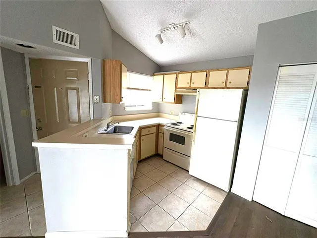 a kitchen with a sink a stove a refrigerator a washer dryer and white cabinets