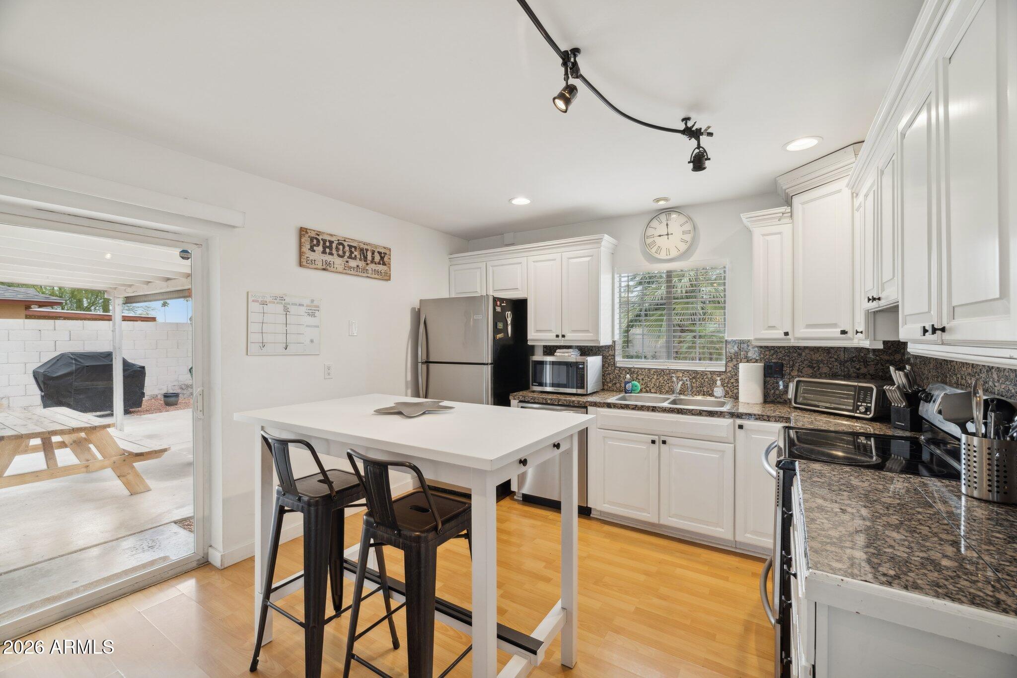 4723 South Country Club Way Tempe, AZ 85282 - Photo 11 of 46 a kitchen with stainless steel appliances kitchen island granite countertop a table chairs and a refrigerator