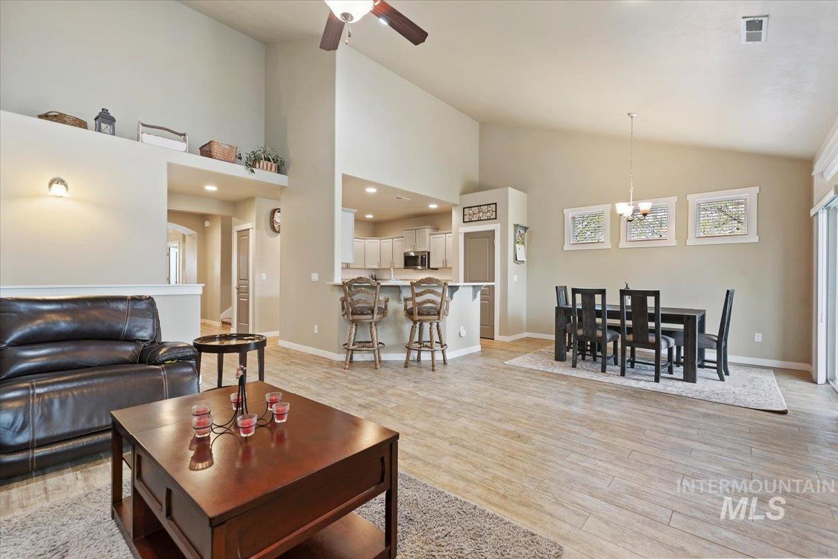 1011 West Riodosa Drive Meridian, ID 83642 - Photo 13 of 38 Living room featuring light wood-type flooring, a ceiling fan, vaulted ceiling, and a chandelier