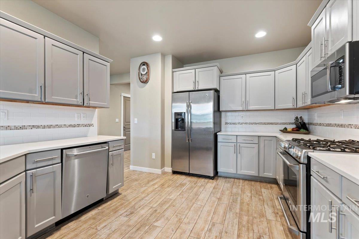 1011 West Riodosa Drive Meridian, ID 83642 - Photo 17 of 38 Kitchen featuring stainless steel appliances, gray cabinets, light wood-style flooring, tasteful backsplash, and recessed lighting