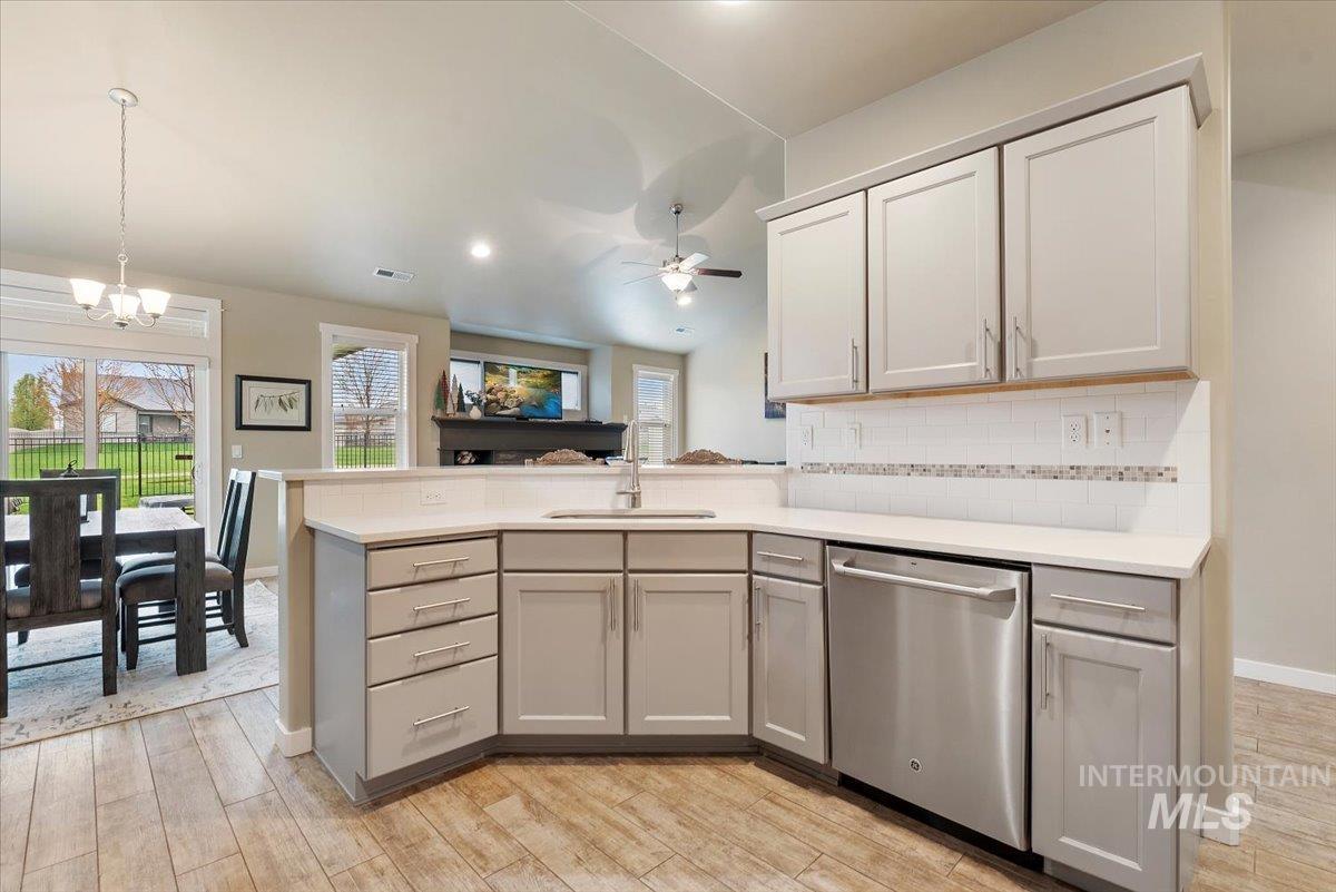 1011 West Riodosa Drive Meridian, ID 83642 - Photo 18 of 38 Kitchen with a peninsula, stainless steel dishwasher, a ceiling fan, light wood finished floors, and backsplash