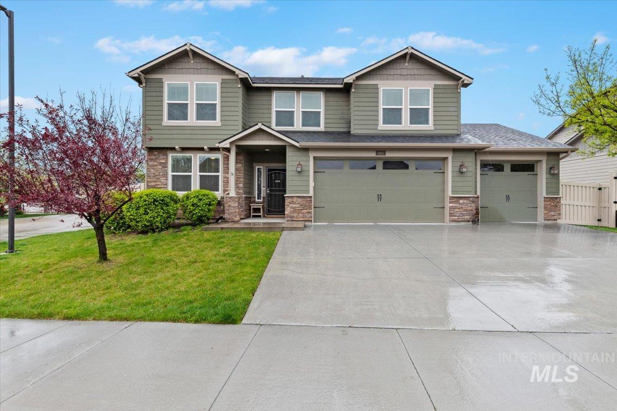 1011 West Riodosa Drive Meridian, ID 83642 - Photo 2 of 38 Craftsman-style house featuring stone siding, a front lawn, concrete driveway, and a garage