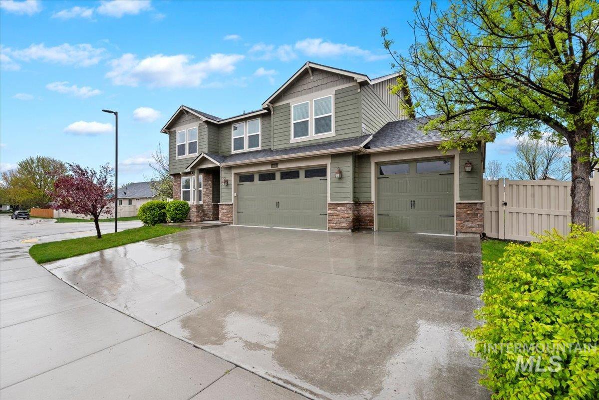 1011 West Riodosa Drive Meridian, ID 83642 - Photo 3 of 38 Craftsman-style home featuring stone siding, an attached garage, driveway, board and batten siding, and a gate