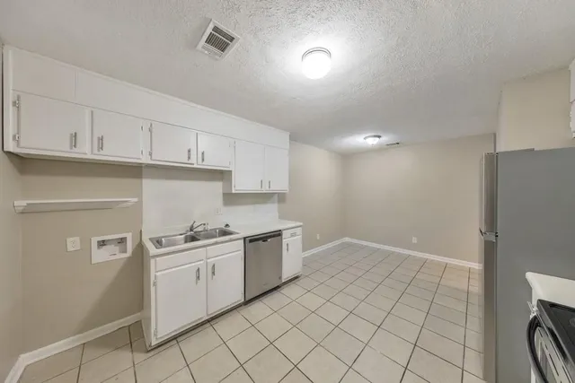 a kitchen with white cabinets a sink and appliances