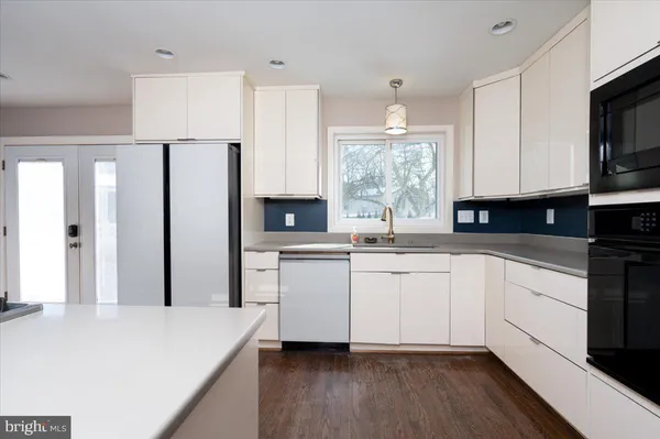 a kitchen with stainless steel appliances granite countertop a refrigerator sink and white cabinets